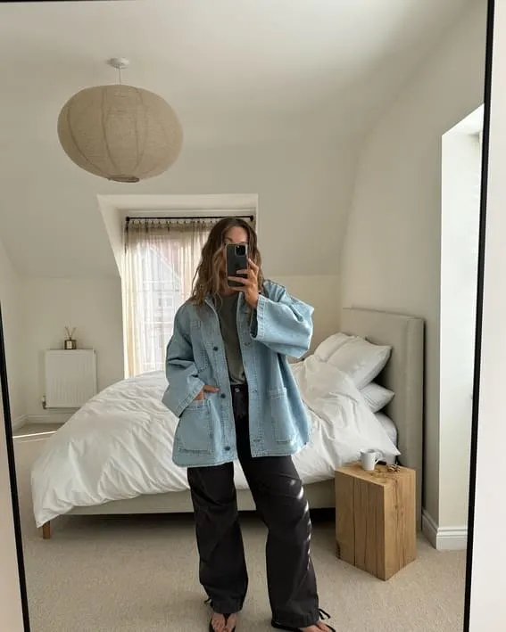 A woman in a casual, large denim jacket and dark trousers.