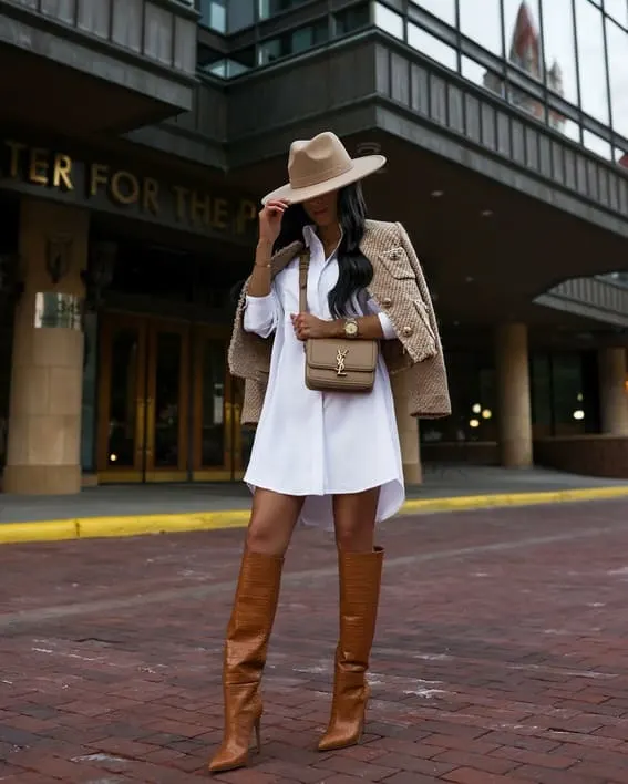 Woman in a chic fall outfit with a fedora and knee-high boots.