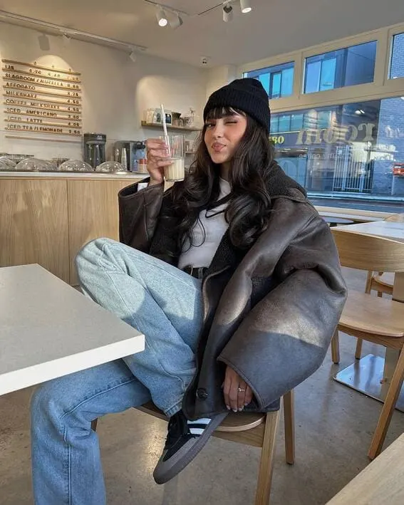 Woman in a cozy fall outfit with a beanie and oversized jacket.