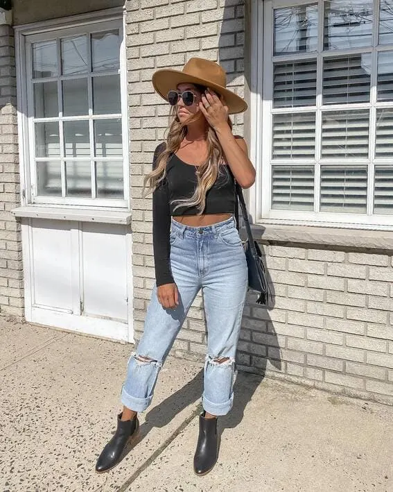 Woman in a trendy fall outfit with a wide-brim hat and ankle boots.