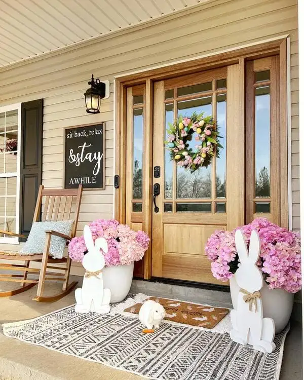 Light wood doors and pink hydrangeas, layered rugs and white wooden bunny cutouts decorate a seasonal front porch.