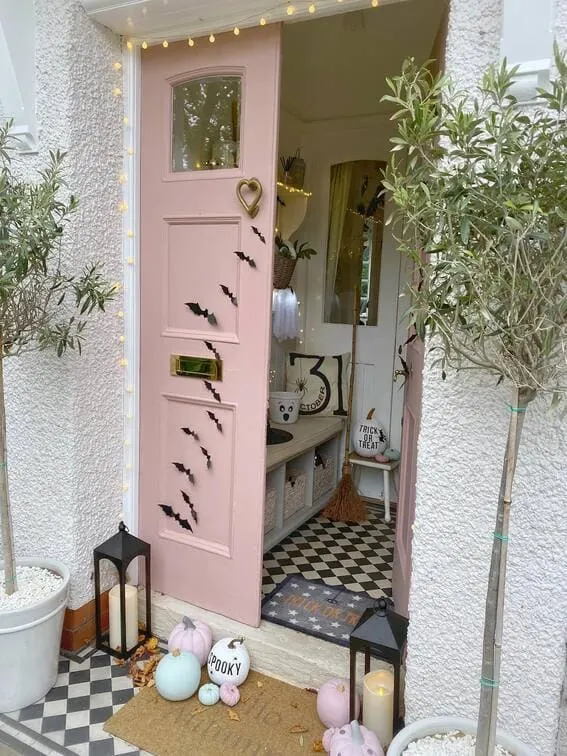 This porch embraces a softer side of Halloween with pastel tones, featuring light pink and mint pumpkins that add a playful, whimsical feel.
