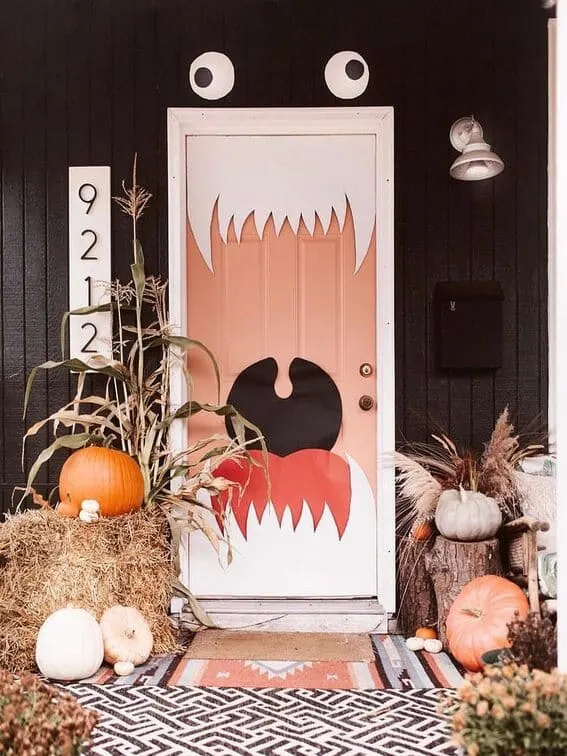 This Halloween porch showcases a standout design—a door turned into a giant monster mouth, with sharp white teeth and oversized googly eyes.