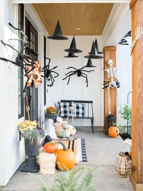 This porch creates a spooky yet inviting atmosphere with floating black witch hats hanging above and oversized spiders creeping along the walls.