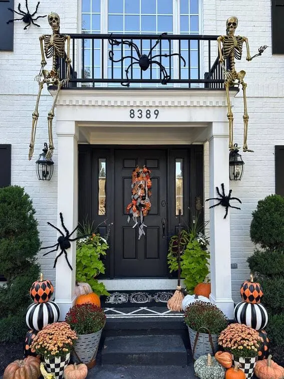 This front porch takes Halloween drama to the next level, with two large skeletons casually perched on the balcony railing, as if watching the scene below.