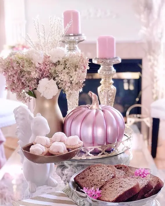 A delicate and elegant tea table setting featuring a metallic pink pumpkin, soft florals, and dainty sweets for a charming fall touch.