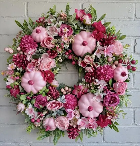 A stunning wreath is adorned with soft pink pumpkins and vibrant colors in magenta, blush, and cream shades.