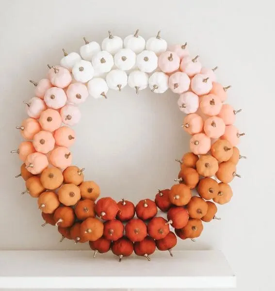 A beautifully crafted ombre wreath featuring mini pumpkins in shades transitioning from deep red to soft white.