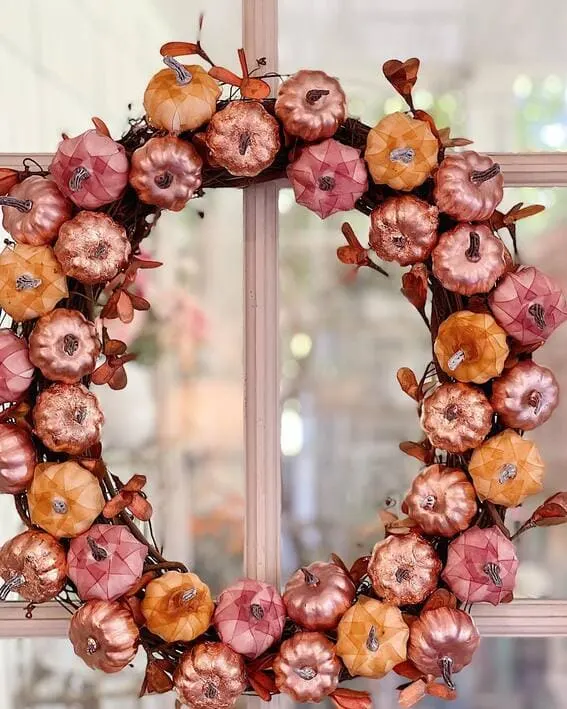 A stunning wreath adorned with metallic copper, blush, and soft orange pumpkins for an elegant fall display.