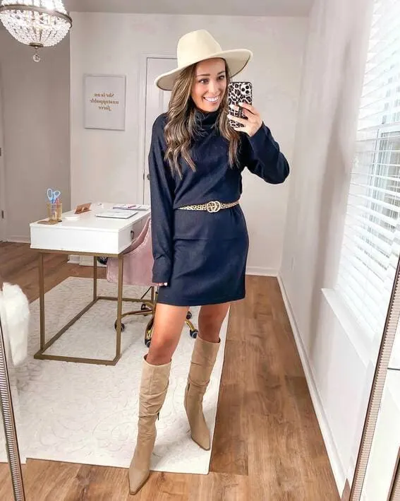 A woman is wearing an black turtleneck sweater and a belt with leopard brown knee high boots.