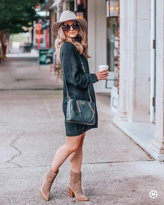 A woman is wearing an oversized turtleneck sweater complete with ankle-high boots, and the wide-brim hat.